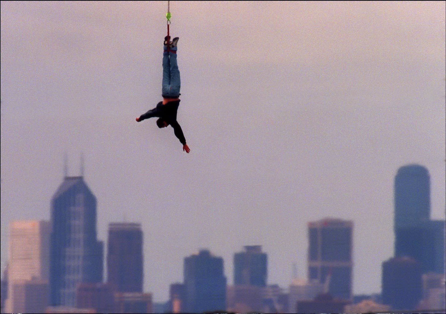 A man bunjee jumping with city backdrop